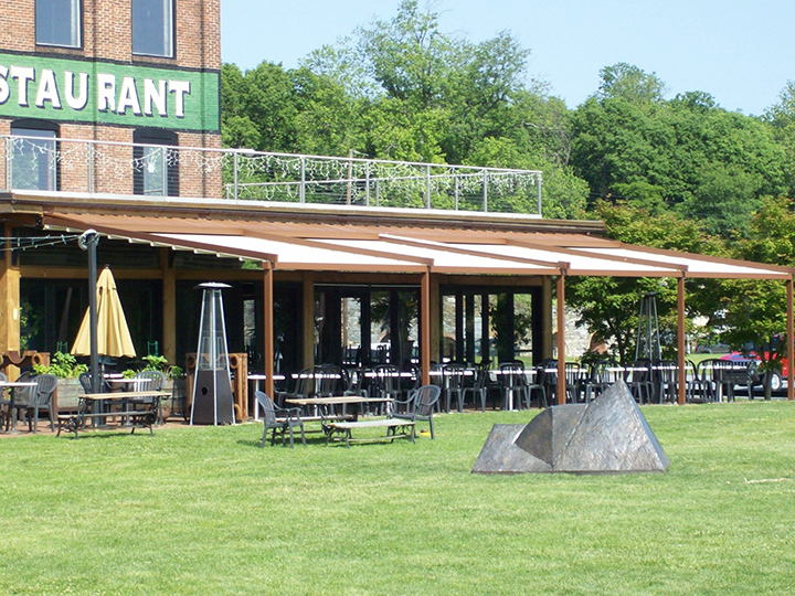 green restaurant sign with pergola extended over outdoor seating area
